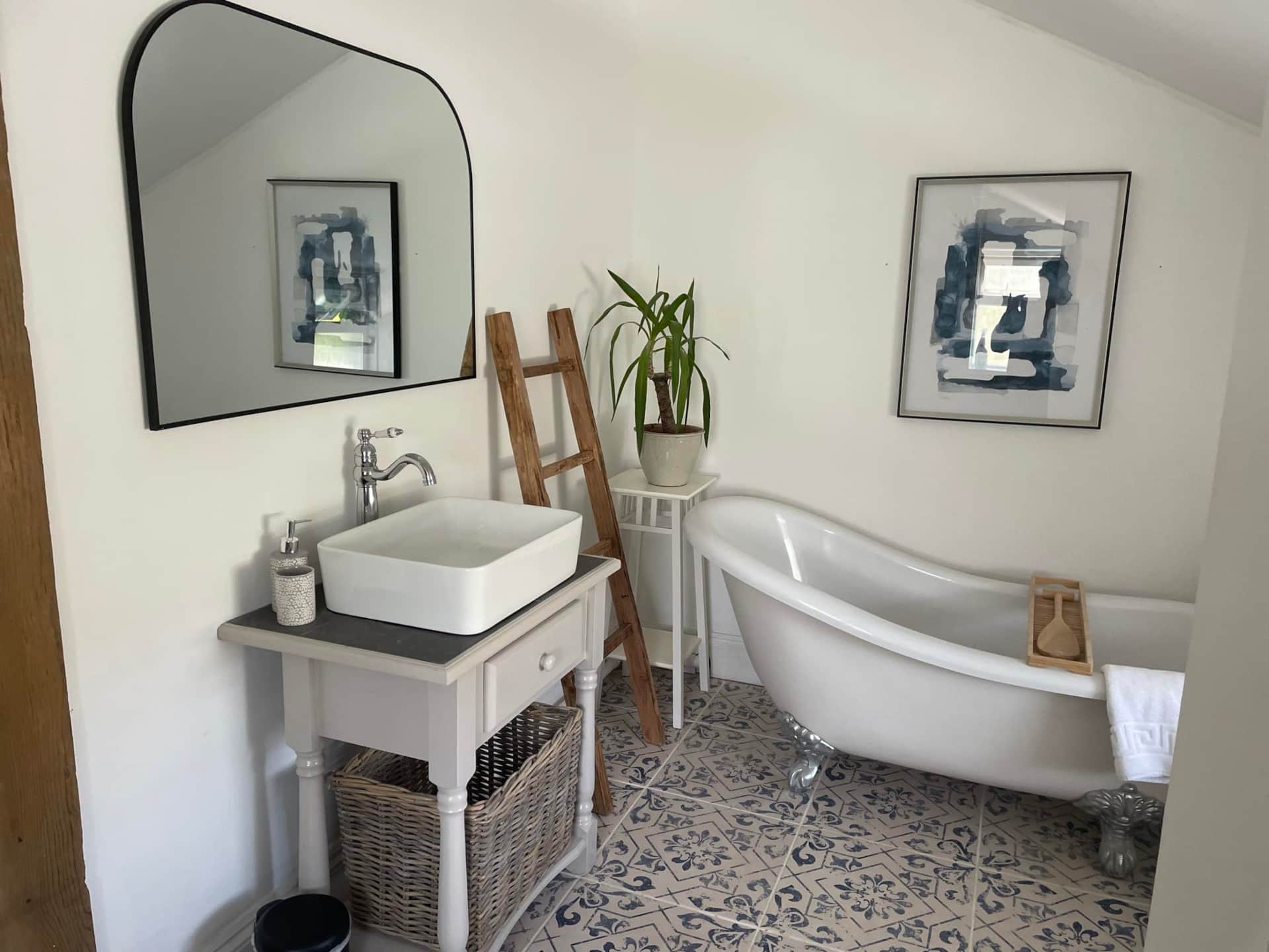 Bathroom with freestanding slipper bathtub, sink, and decorative elements.
