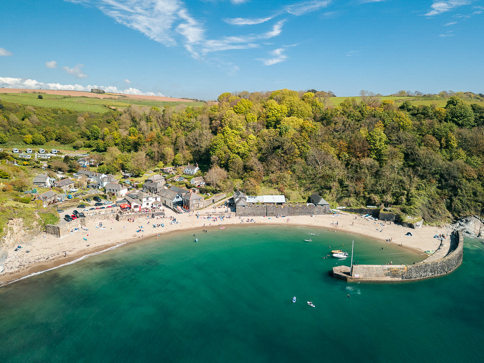 Aerial view of a Polkerris village with a beach and clear blue water.