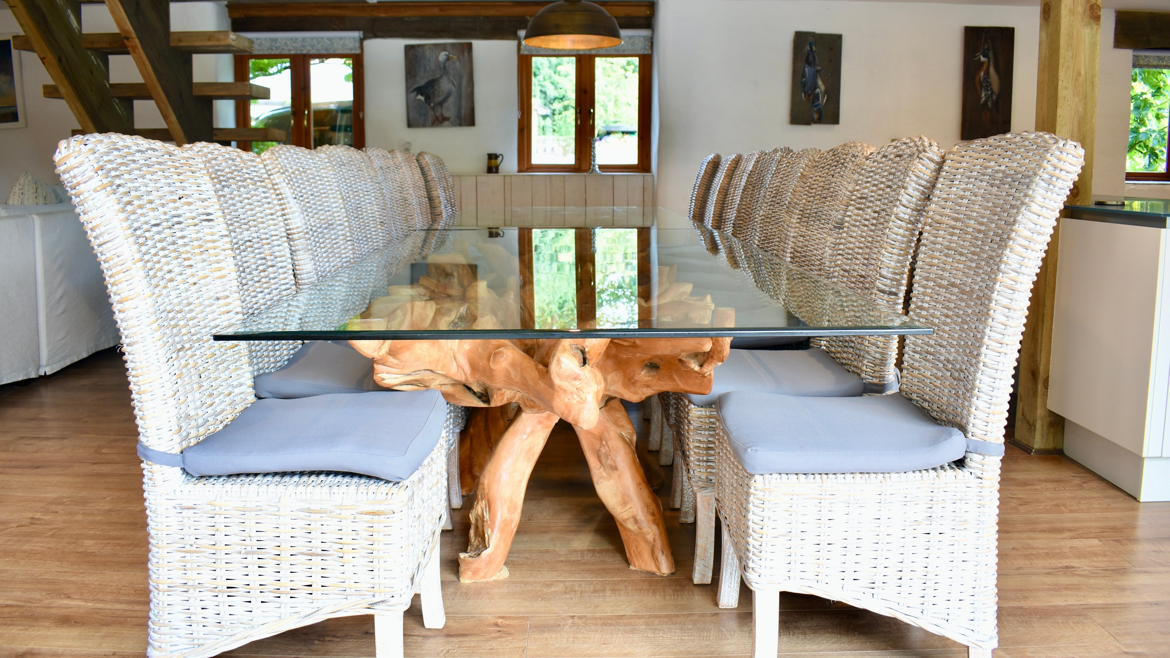 Dining area with wicker chairs and a glass table in a home setting.
