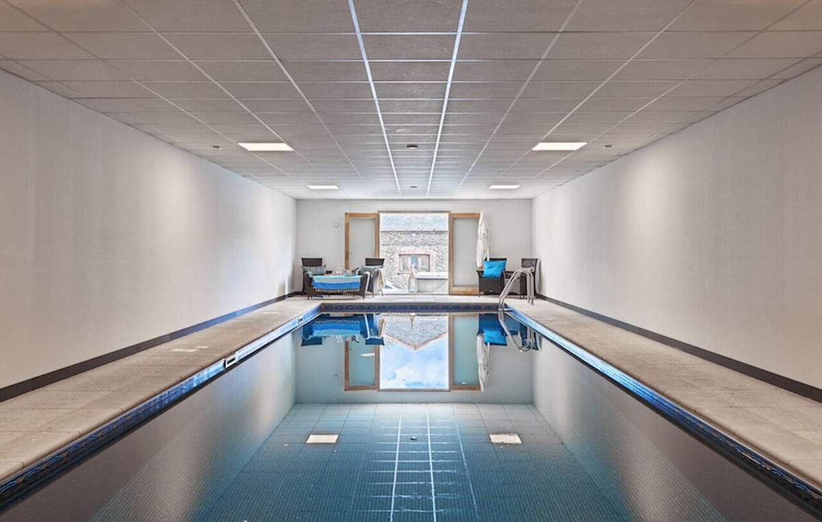 Indoor pool with white walls and a glass door leading to an outdoor area.