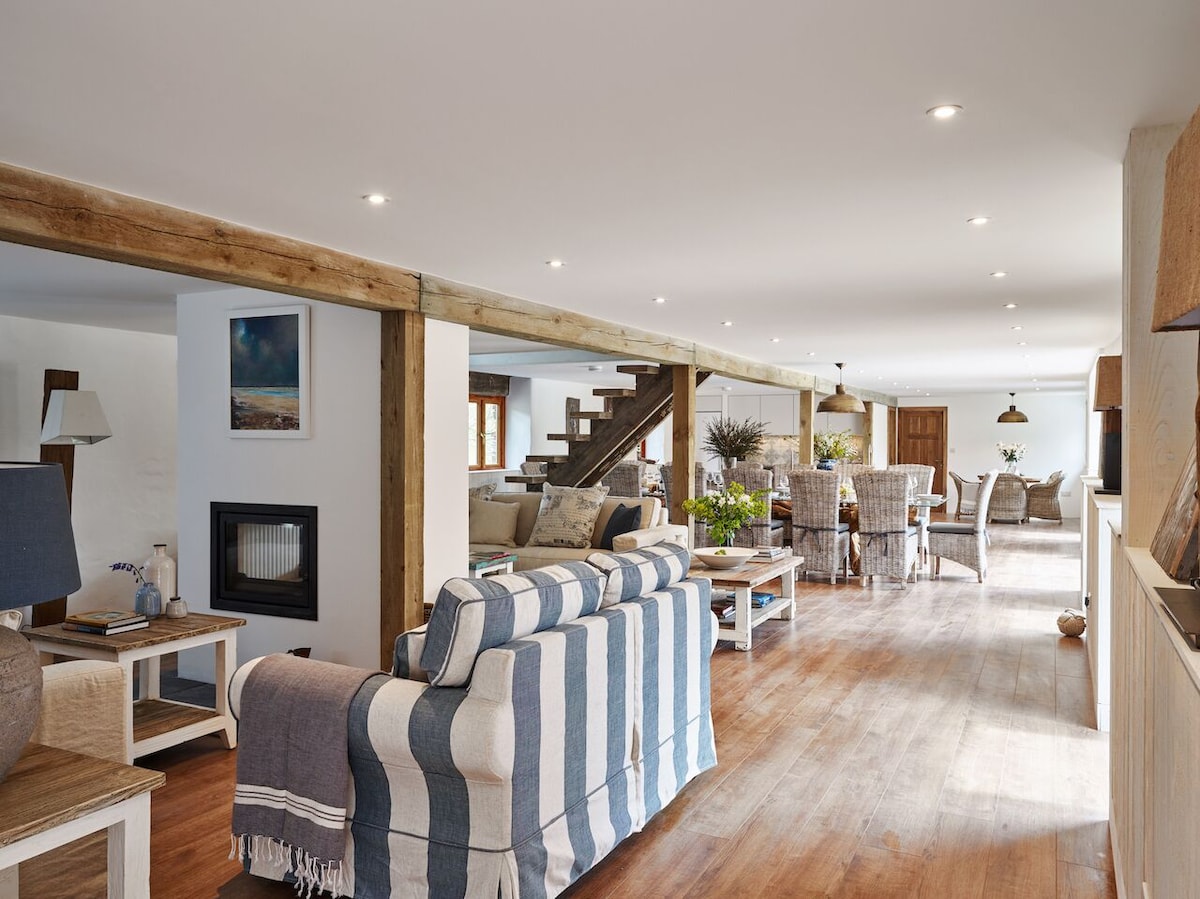 Living room with striped sofa, fireplace, and open-plan dining area.