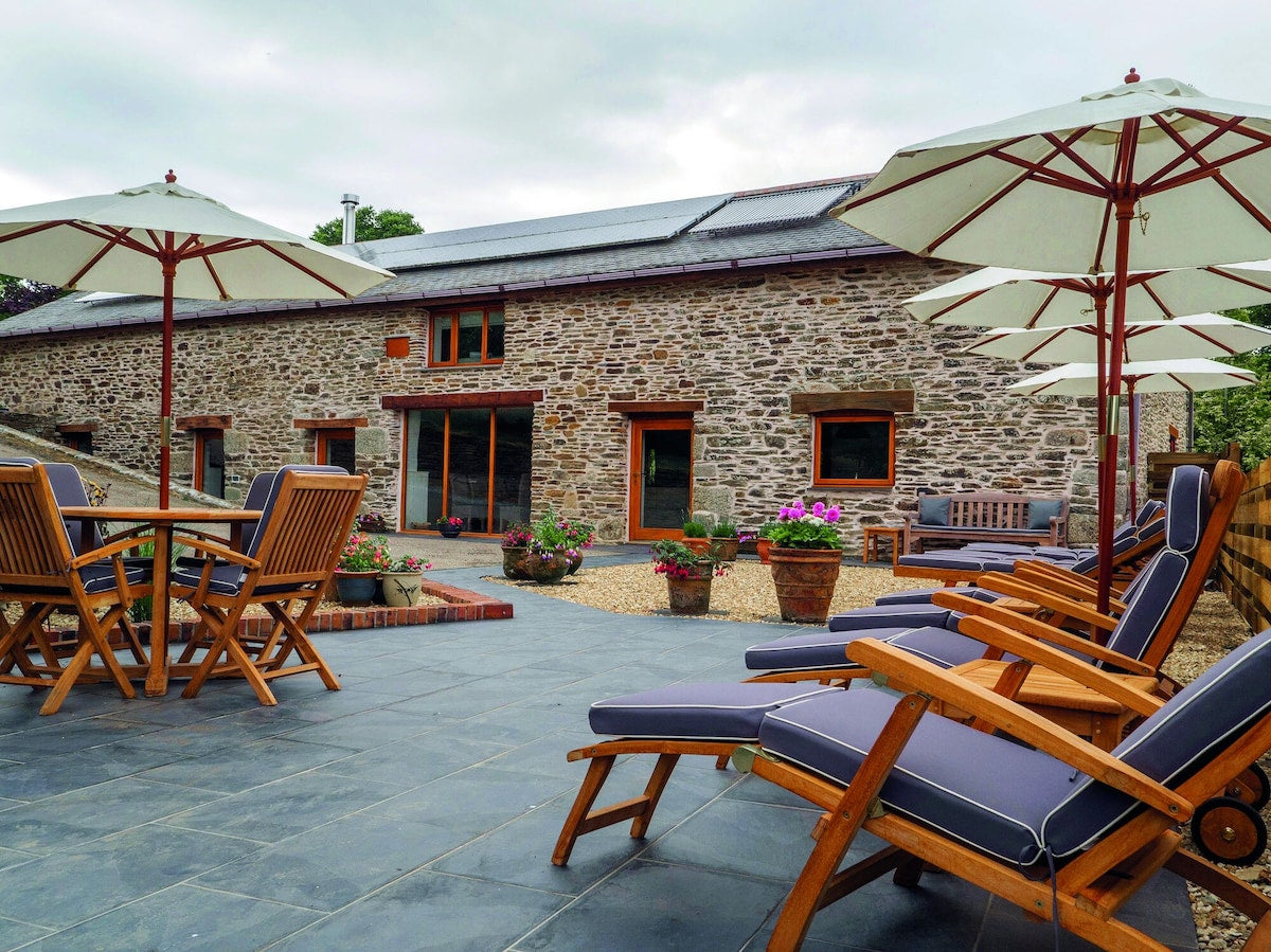 Outdoor seating area with wooden chairs and tables in front of a stone building.